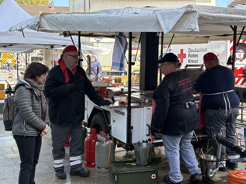 Helfer*innen und Mitglieder der DRK-Bereitschaft bei der Tour d'Energie 2026 in Göttingen beim Verpflegungsdienst. Mitglieder der DRK-Bereitschaft kochen in der Feldküche. Kreisbereitschaftsleiter Franz Beckmann spricht mit DRK-Kreisgeschäftsführerin Petra Reußner