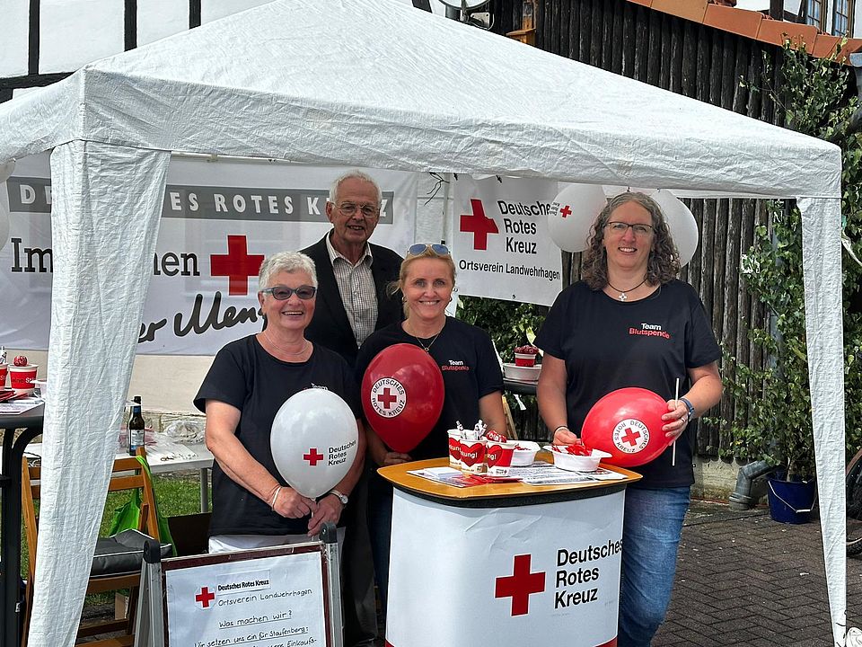 2026_09_15_Dorffest_Stand_Mitgliedergewinnung_OV_Landwehrhagen__1_.jpg Mitglieder des DRK-Ortsvereins Landwehrhagen im DRK-Kreisverband Göttingen-Northeim e. V. an einem DRK-Stand mit Luftballons und Pavillion