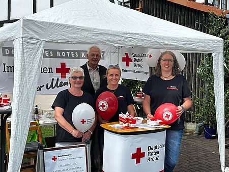 Mitglieder des DRK-Ortsvereins Landwehrhagen im DRK-Kreisverband Göttingen-Northeim e. V. an einem DRK-Stand mit Luftballons und Pavillion