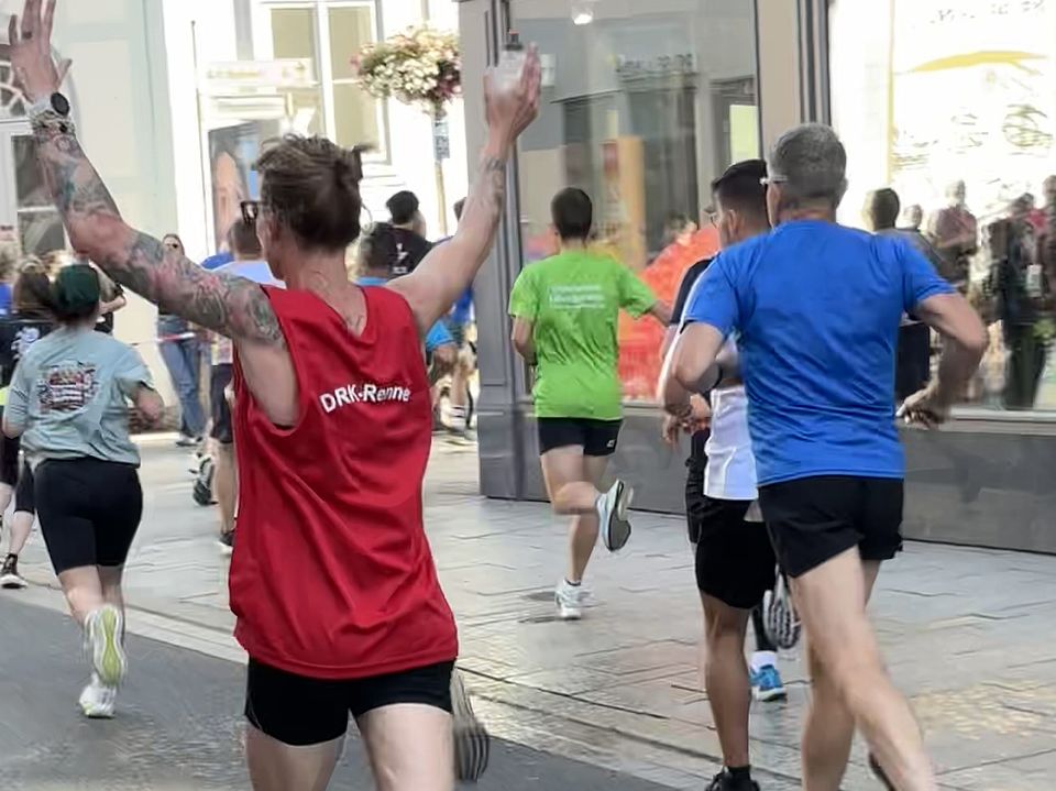 2026_07_01_Altstadt-Läuferinnen_während__4_.jpeg DRK-Läufer*in mit hoch erhobenen Armen beim Altstadtlauf Göttingen 2026 auf der Strecke in der Innenstadt