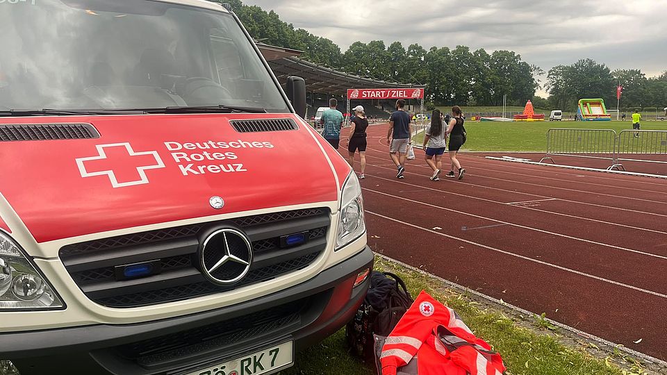 DRK-Bereitschaft beim Sanitätsdienst beim Frühjahrsvolkslauf in Göttingen im Jahnstadion: DRK-Einsatzwagen im Stadion, im Hintergrund der Start- und Zielbereich und Rennstrecke