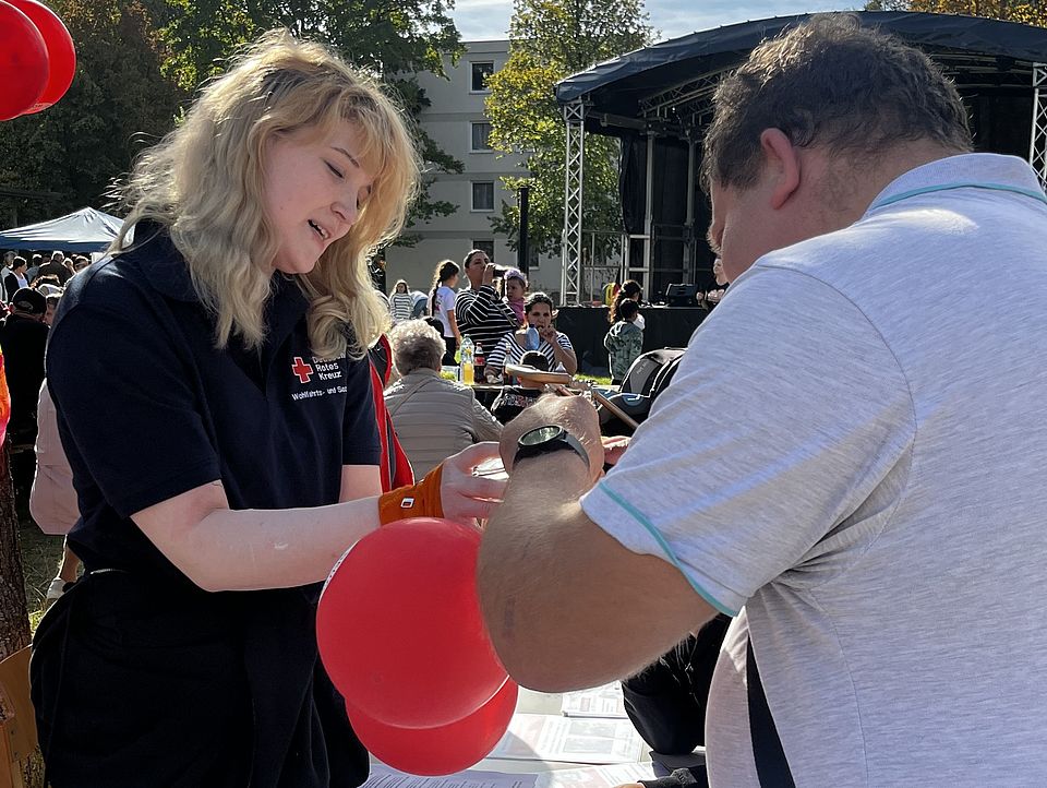 Menschen und Bundesfreiwilligendienst-leistende mit Luftballons am Stand des DRK-Spendenzentrums beim interkulturellen Nachbarschaftsfest der Vielfalt in Göttingen-Grone