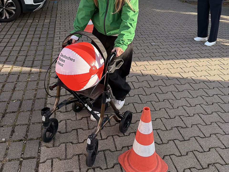 Schülerin der BBS Einbeck balanciert einen DRK-Wasserball auf einem Rollator, Mitmachaktion am DRK-Stand auf der Einbecker Ausbildungsmesse