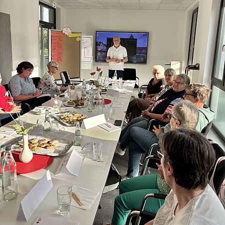 Zukunftswerkstatt der DRK-Ortsvereine in der Zimmermannstraße 4 in Göttingen: Teilnehmende im Workshop an gedecktem Tisch, Präsentation im Hintergrund.