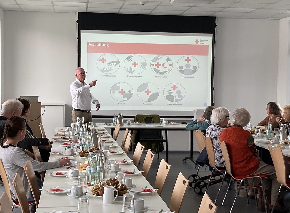 Bisheriger Vorsitzender Frank Wiegelmann hält eine Präsentation auf der Jahreshauptversammlung des DRK-Ortsverein Göttingen, an den Tischen Mitglieder