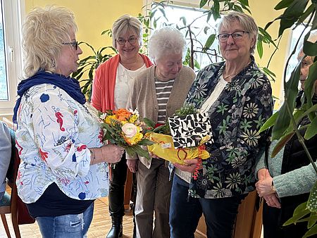 Mitglieder des DRK-Ortsvereis Uslar stehen bei einer Geschenküberhabe mit Blumen bei einer Ehrung der und Verabschiedung der bisherigen Vorsitzenden Frau Andermann