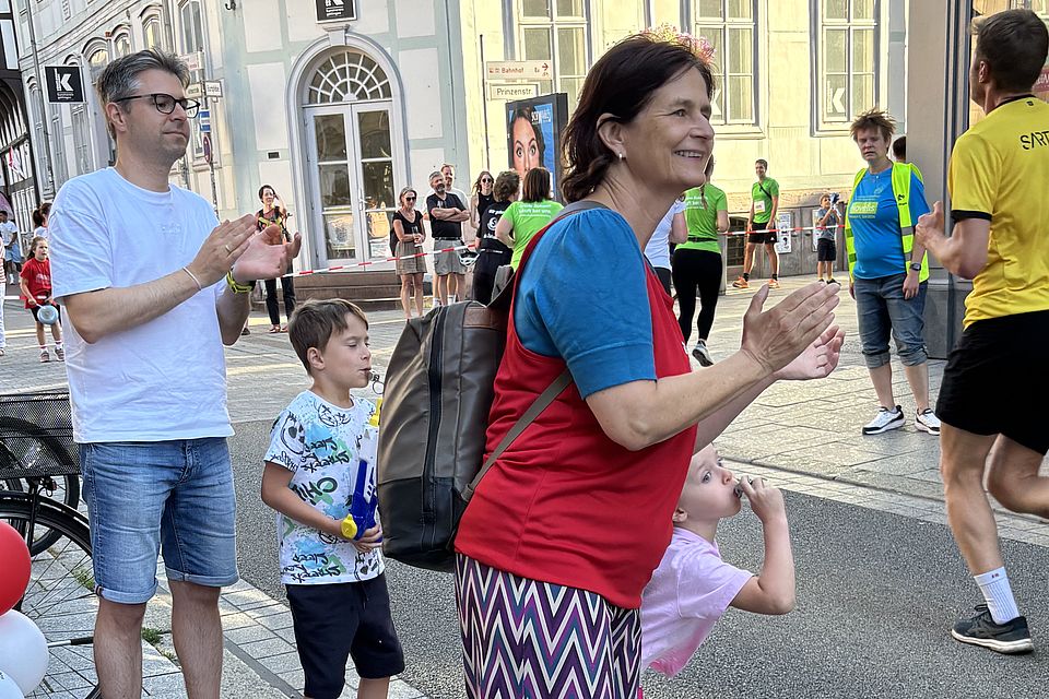 2026_07_01_Altstadt-Läuferinnen_während__11_.jpeg DRK-Läuferinnen beim Altstadtlauf Göttingen 2026 passieren Zuschauerinnen in der Innenstadt. DRK-Kreisgeschäftsführerin Petra Reußner klatscht am Rand des Altstadtlaufes für die Läufer*innen gemeinsam mit anderen Personen