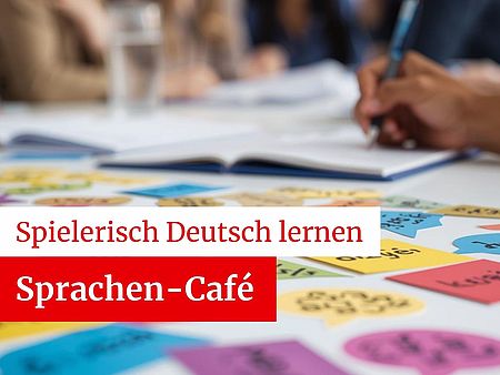 Menschen an einem Tisch im Hintergrund sichtbar, mit vielen bunten Karten zum Sprachenlernen auf dem Tisch, eine Person schreibt etwas. Bewerbung des Sprachen-Cafes des DRK-OV Göttingen "Spielerisch Deutsch lernen"
