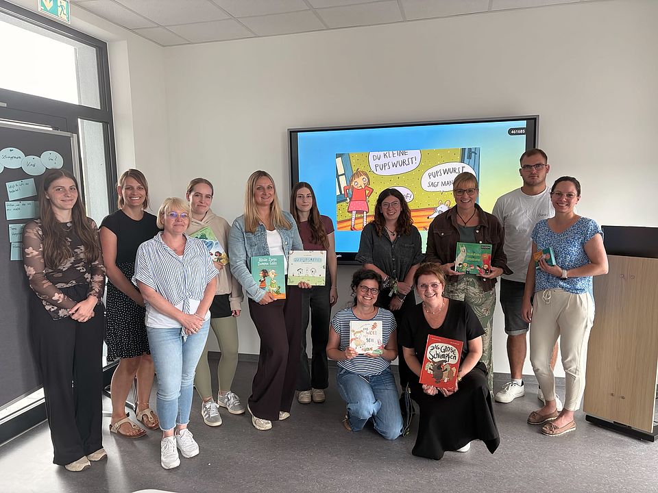 2026_07_07_Workshop_Sprache_und_Adultismus_für_pädagogische_Fachkräfte__32_.jpeg Gruppe pädagogischer Fachkräfte des DRK‑Kreisverbands Göttingen‑Northeim e. V. in einem Seminarraum in Göttingen (Zimmermannstraße 4). Einige Personen halten Kinderbücher und Materialien zum Thema Sprache und Adultismus; im Hintergrund sind Flipchart und Präsentationsfolie mit Beispielen sichtbar.