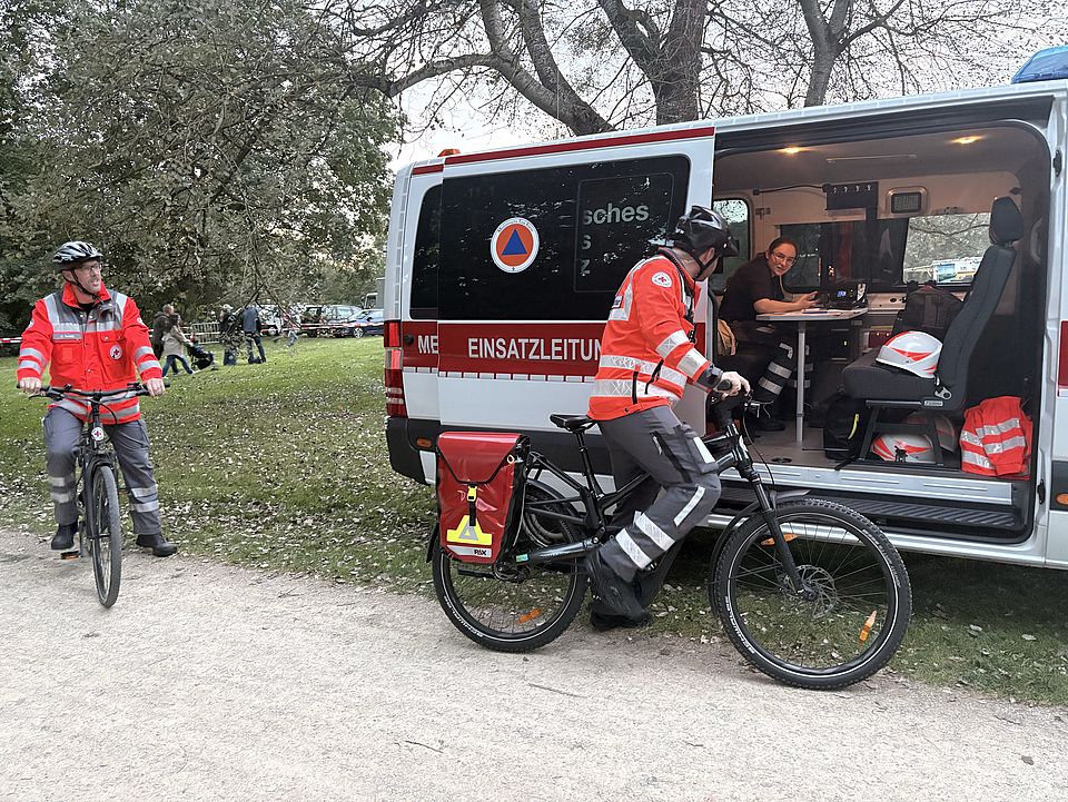 2026_09_26_Lichterlauf_am_Kiessee__12_.jpg DRK-Bereitschaft Göttingen vor Einsatzfahrzeug mit E-Bikes der neuen DRK-Fahrradstaffel am Göttinger Kiessee beim Lichterlauf, Abstimmung mit Einsatzkräften am Einsatzleitfahrzeug
