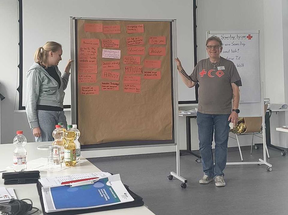 2026_05_31_Ausbilderschulung_Erste_Hilfe_vom_DRK-Landesverband__4_.jpg DRK-Ausbilderschulung: Zwei Teilnehmende präsentieren Ergebnisse an Pinnwand mit Haftnotizen im Seminarraum.
