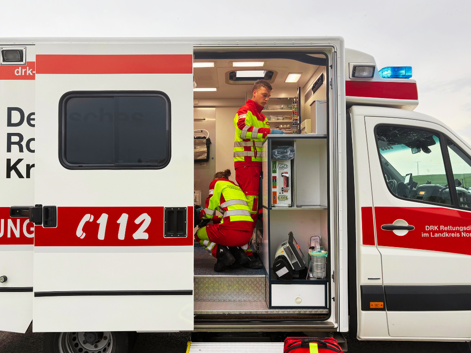2026_08_11_Tag_der_Rettung_Save_the_date.png Rettungswagen des DRK-Kreisverbandes Göttingen-Northeim e. V. mit offener Tür und Rettungskräften