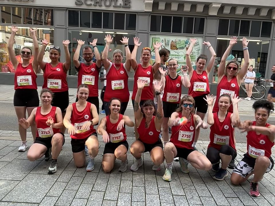 2026_07_01_Altstadt-Läuferinnen_vorher__6_.jpeg Mehrere Teilnehmende in roten DRK-Laufshirts stehen als Gruppe zusammen und heben die Arme. Das Team tritt gemeinsam beim Altstadtlauf in Göttingen an.