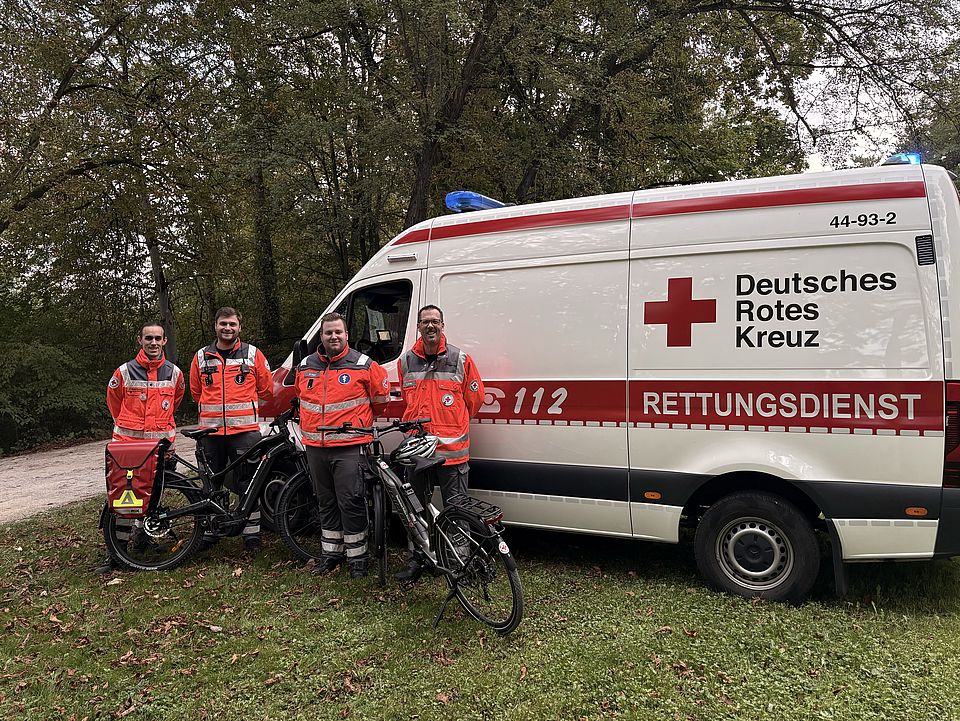 2026_09_26_Lichterlauf_Fahrradstaffel_und_Einsatzfahrzeug_mit_Einsatzkräften.jpg DRK-Bereitschaft Göttingen vor Einsatzfahrzeug mit E-Bikes der neuen DRK-Fahrradstaffel am Göttinger Kiessee beim Lichterlauf, Gruppenfoto