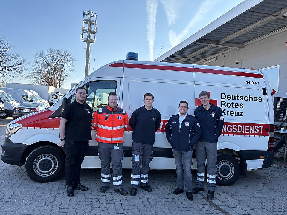 Eine Gruppe von Einsatzkräften des DRK‑Sanitätsdienstes der DRK-Bereitschaft steht vor einem Rettungswagen auf dem Außengelände des neuen DRK‑Spendenzentrums Göttingen. Die Kräfte begleiteten die Einweihungsfeier am 3. März und unterstützen die Veranstaltung sicherheitstechnisch