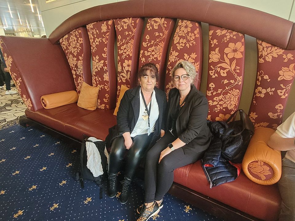 Zwei Mitarbeiterinnen des DRK-Hausnotrufs sitzen auf einem sehr großen Sofa bei den Kasseler Hausnotruftagen