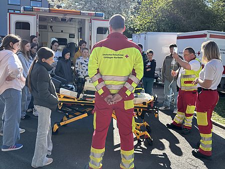 Zukunftstag beim DRK-Kreisverband Göttingen-Northeim e. V.: Kinder und Jugendliche verschiedener Göttinger Schulen zu Besuch. Führung der Gruppe über den Hof - ein Rettungssanitäter des DRK zeigt einen Rettungswagen