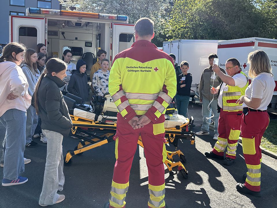 Zukunftstag beim DRK-Kreisverband Göttingen-Northeim e. V.: Kinder und Jugendliche verschiedener Göttinger Schulen zu Besuch. Führung der Gruppe über den Hof - ein Rettungssanitäter des DRK zeigt einen Rettungswagen