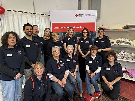 Eine große Gruppe von ehrenamtlichen und hauptamtlichen Mitarbeitenden des DRK‑Kreisverbands Göttingen‑Northeim steht im Spendenzentrum vor einem DRK‑Banner mit der Aufschrift ‚Aus Liebe zum Menschen‘. Die Aufnahme zeigt das engagierte Team, das die Einweihungsfeier des neuen Spendenzentrums am 3. März gestaltet und begleitet hat