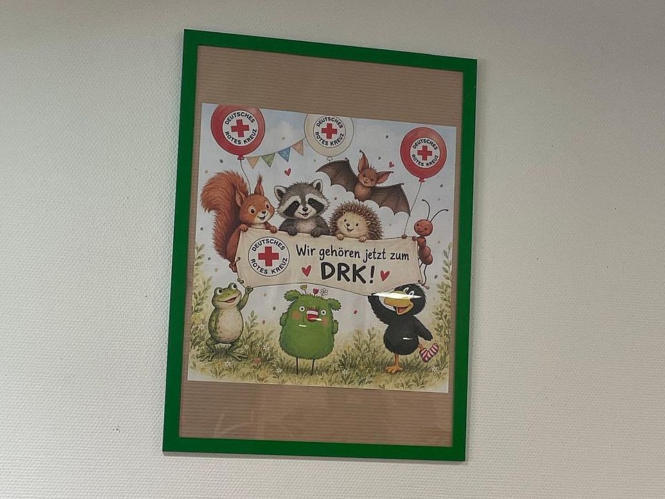 Plakat an der Wand in einem Rahmen mit der Aufschrift "Wir gehören jetzt zum DRK" in der DRK-Kita Löwenhagen