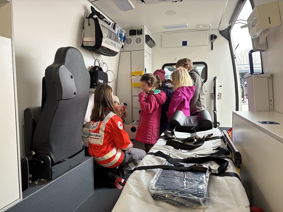 Kinder der Evangelischen Familienbildungsstätte dürfen bei der Familienführung einen Rettungswagen des DRK‑Kreisverbandes Göttingen‑Northeim von innen besichtigen und medizinische Ausstattung kennenlernen.