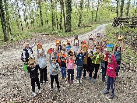 Kinder beim Walderlebnistag des DRK-Ortsvereins Harste in einer Gruppe im Wald, in der Hand halten sie ihre gebauten Nistkästen in die Höhe