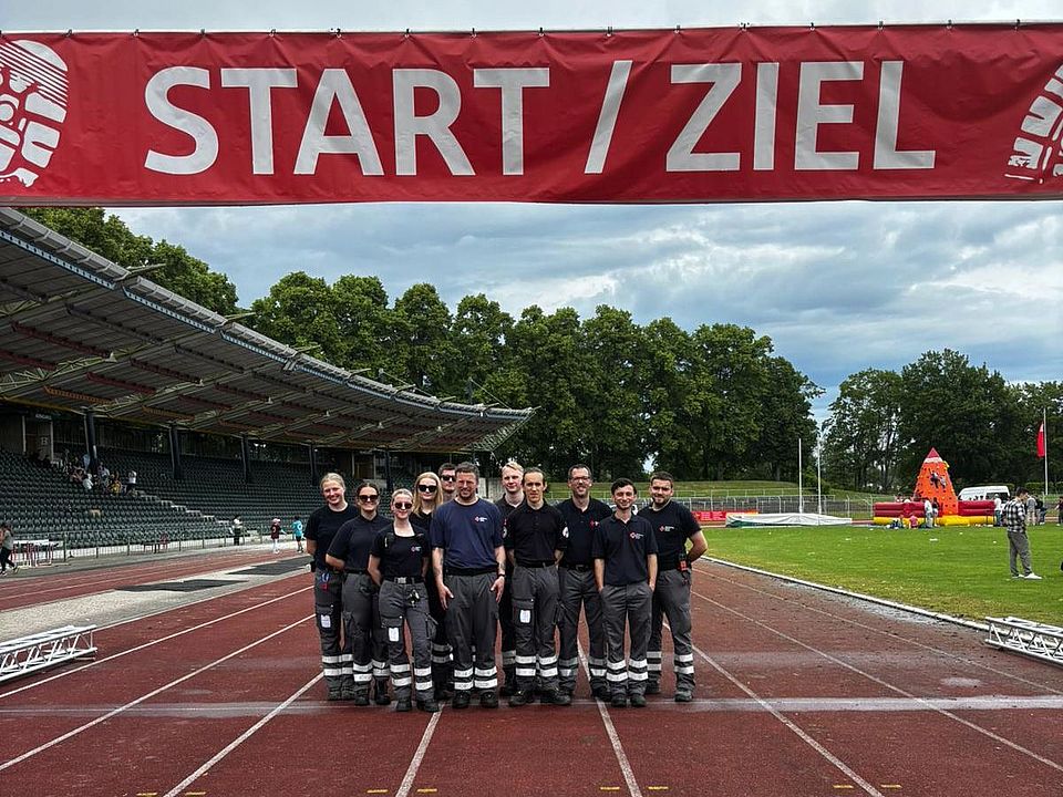 DRK-Bereitschaft beim Sanitätsdienst beim Frühjahrsvolkslauf in Göttingen im Jahnstadion: Gruppenfoto der Mitglieder im Ziel- und Startbereich, unter einem Banner auf der Rennstrecke