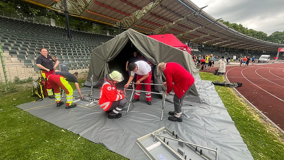 DRK-Bereitschaft beim Sanitätsdienst beim Frühjahrsvolkslauf in Göttingen im Jahnstadion: Bereitschaftsmitglieder in Uniform bauen das Hilfszelt im Stadion  auf
