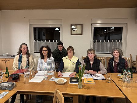 Sechs Anwesende auf der Jahreshauptversammlung des DRK-Ortsvereins Immensen sitzen an einem Tisch und lächeln in die Kamera