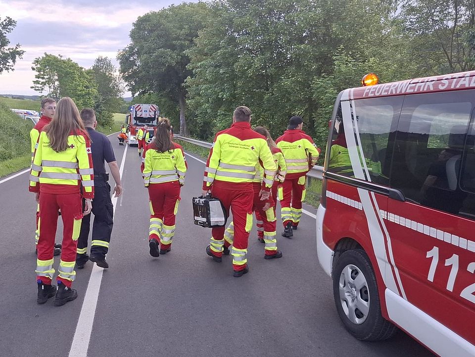2026_06_03_Rettungsdienstübung_Uslar_mit_Feuerwehr_-_Rettung_in_Höhe_und_Tiefe__5_.jpeg DRK-Kreisverband Göttingen-Northeim e. V. und Feuerwehr bei Übung „Rettung in Höhe und Tiefe“ in Uslar: Einsatzkräfte gehen mit Ausrüstung auf Landstraße zu Feuerwehrfahrzeug