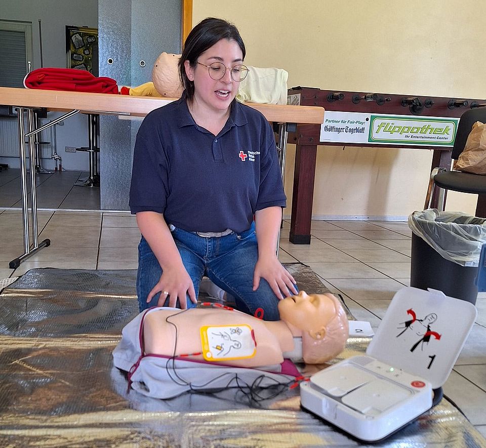DRK-Schulung „Erste Hilfe am Kind“: Trainerin demonstriert Wiederbelebung mit Übungspuppe und Defibrillator
