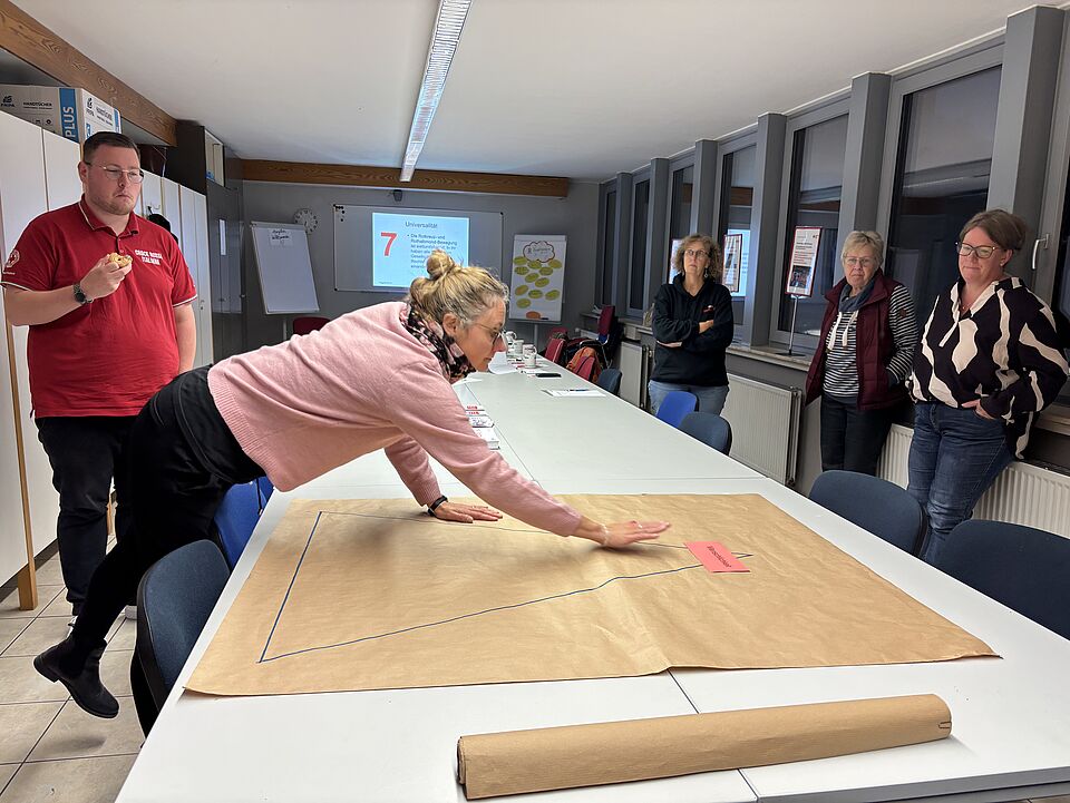 2026_10_23_Workshop_in_Northeim__1_.jpeg Während des Workshops stehen die Referierenden vor der Gruppe und führen durch die Themen rund um Geschichte, Grundsätze und Strukturen des Deutschen Roten Kreuzes. Die Veranstaltung richtete sich an Interessierte sowie Vertreterinnen und Vertreter der DRK-Ortsvereine und des Jugendrotkreuzes.