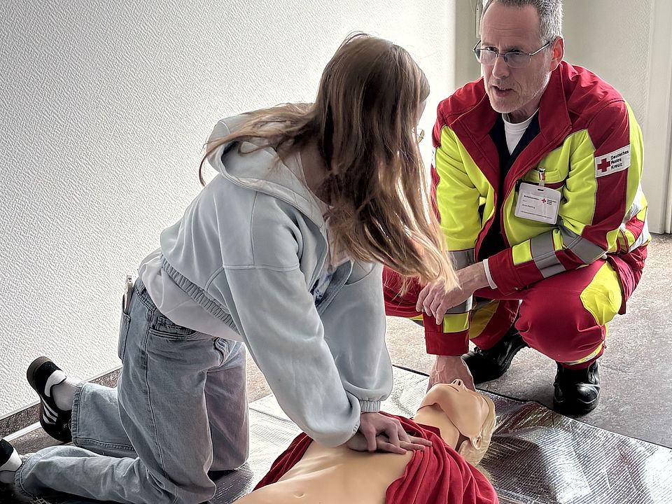 Zukunftstag beim DRK-Kreisverband Göttingen-Northeim e. V.: Kinder und Jugendliche verschiedener Göttinger Schulen zu Besuch. Rettungssanitäter zeigt einer Schülerin Erste-Hilfe an einer Puppe