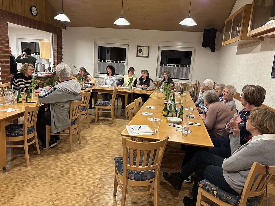 Mitglieder des DRK-Ortsvereins Immensen sitzen am an einem Tisch, der U-förmig gestellt ist, zur Jahreshauptversammlung. Auf dem Tisch stehen Flaschen, es ist ein geselliges Beisammensein