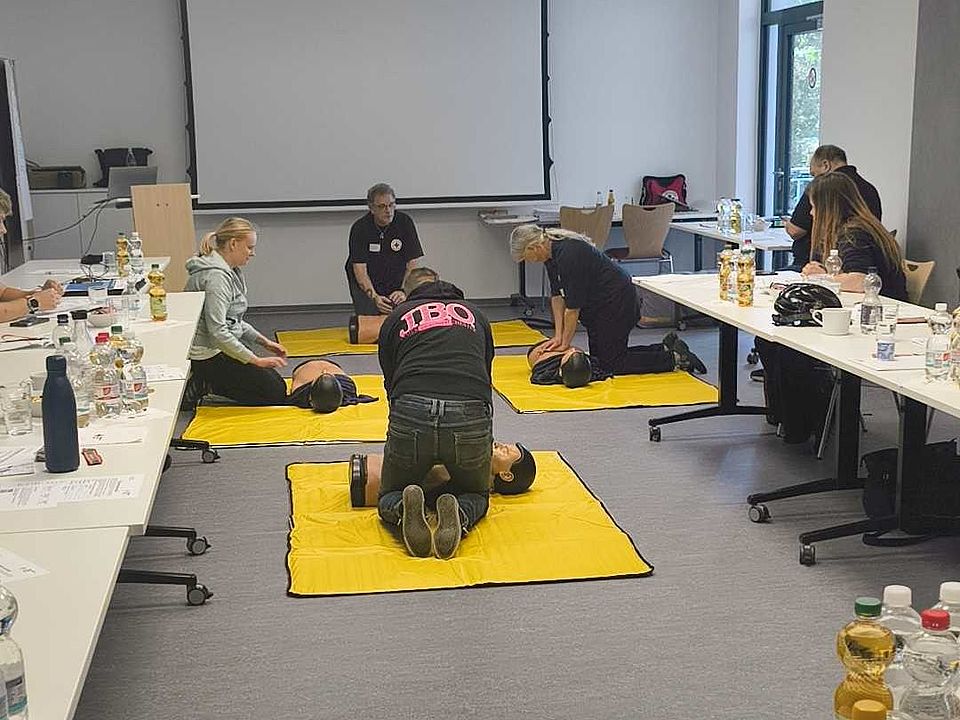 2026_05_31_Ausbilderschulung_Erste_Hilfe_vom_DRK-Landesverband__1_.jpg Erste-Hilfe-Fortbildung des DRK: Teilnehmende üben Herz‑Lungen‑Wiederbelebung auf Übungspuppen auf gelben Matten im Seminarraum.