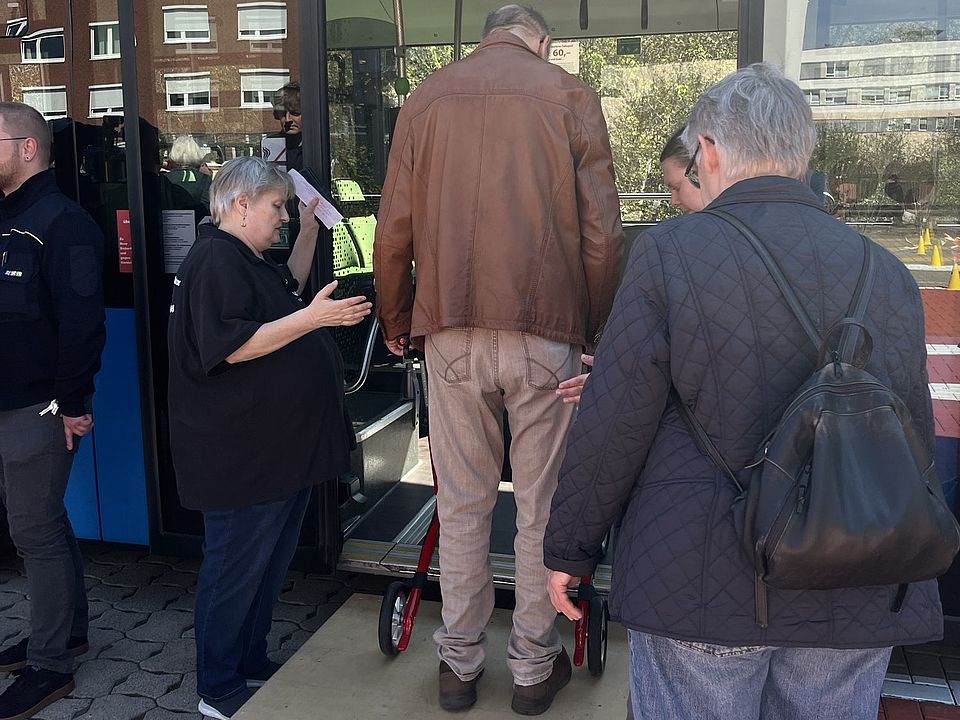Teilnehmende am Stadtbustraining des DRK-Ortsvereins Göttingen in Kooperation mit dem SC Hainberg. Teilnehmende üben über eine Rampe das Einsteigen in den Bus mit einem Rollator