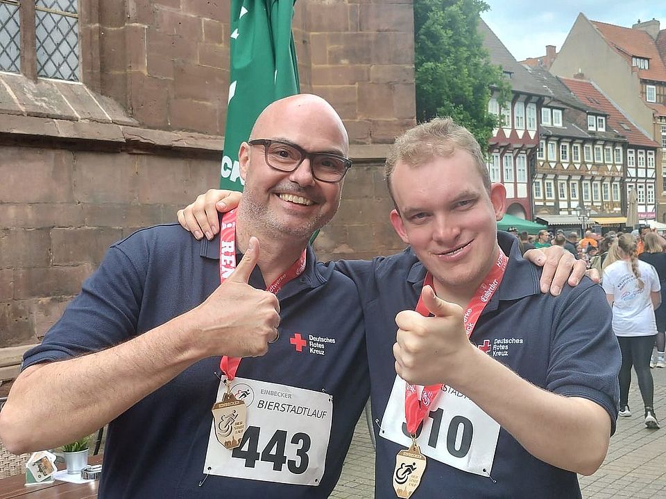 Simon Hartmann und Leon vom FED des DRK Arm in Arm mit Daumen hoch beim Bierstadtlauf in Einbeck 2026