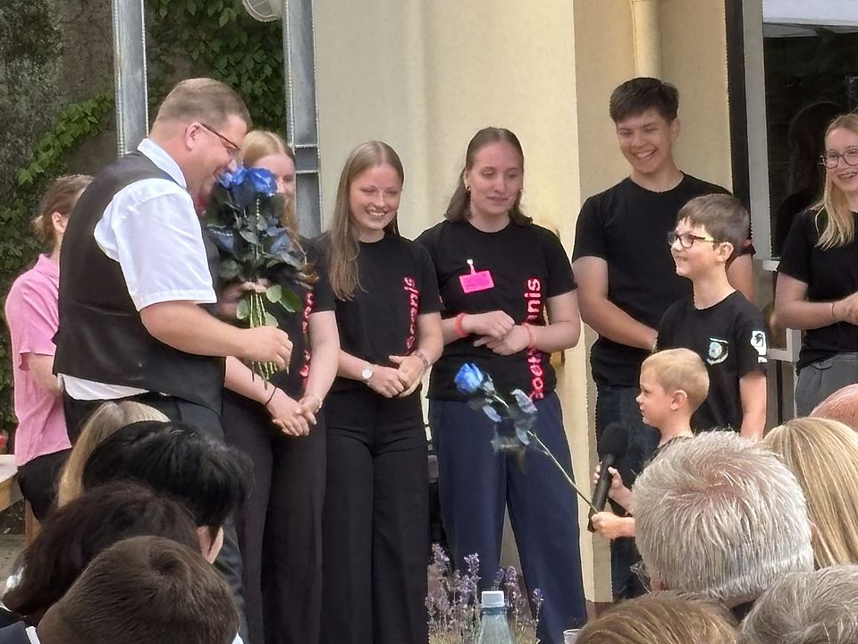 2026_07_04_Bundesverdienstkreuz_Jan_Störmer__3_.jpeg Jugendliche und Kinder aus dem DRK überreichen Blumen an Jan Störmer bei Verleihung des Bundesverdienstkreuzes im DRK-Kreisverband Göttingen-Northeim e. V. im Haus des Jugendrotkreuzes Einbeck