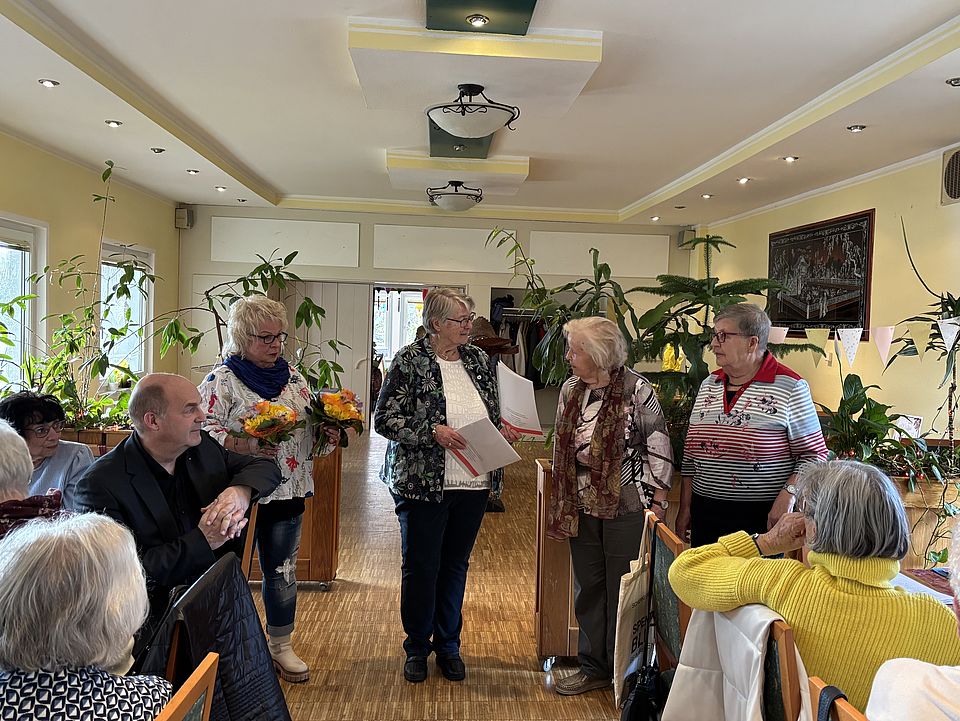 2026_03_JHV_2026-Neuer_Vorstand___Vorsitzende_Uslar__18_.jpeg Mitglieder des DRK-Ortsvereins Uslar stehen im Halbkreis bei einer Ehrung der und Verabschiedung der bisherigen Vorsitzenden Frau Andermann