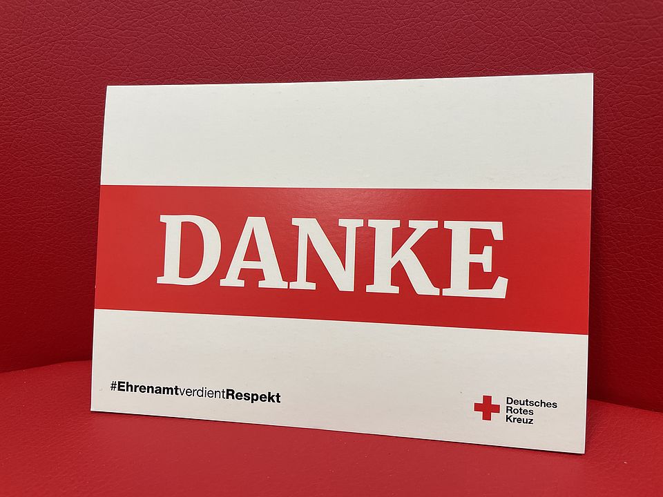 2025_12-05_Dankeskarte DRK Eine Postkarte in rot-weiß, auf der 'Danke' steht vom DRK für das Ehrenamt