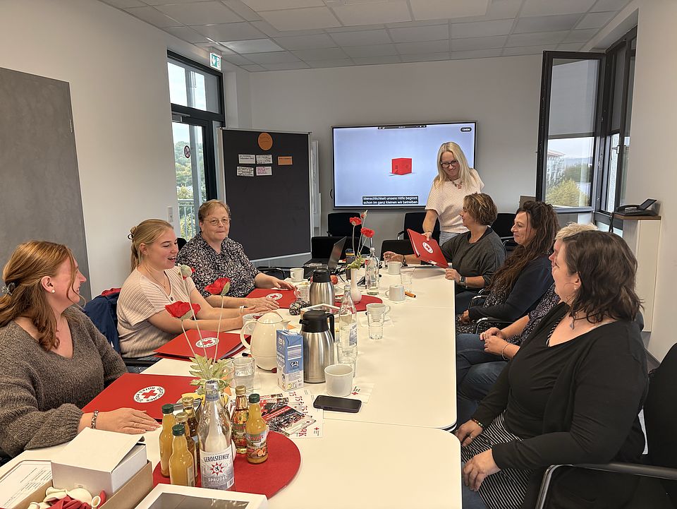 2026_10_01_Teamtag_Kita_Löwenhagen__17_.jpg Die Teilnehmenden sitzen an einem Besprechungstisch im DRK-Kreisverband Göttingen-Northeim und tauschen sich über die künftige Zusammenarbeit aus. DRK-Unterlagen und Informationsmaterialien begleiten den Auftakt nach dem Trägerwechsel.