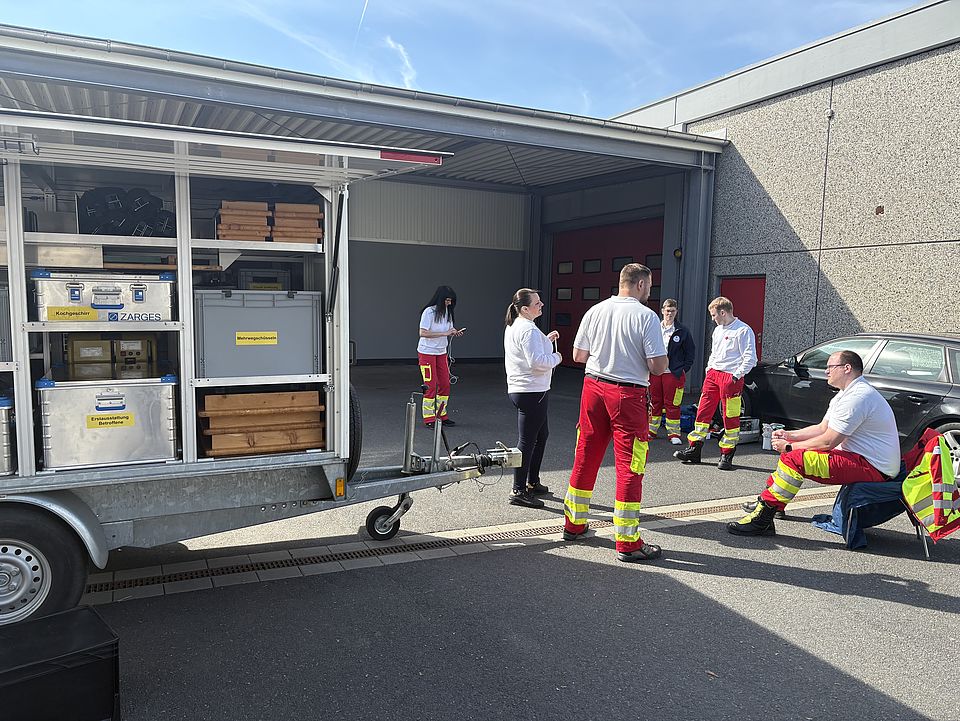 Übung des DRK-Rettungsdienstes auf dem Hof des DRK-Kreisverbandes Göttingen-Northeim e. V. in Göttingen. Im Vordergrund steht ein Materialwagen, daneben Rettungskräfte bei der Übung zum Thema "Versorgung von Trauma"