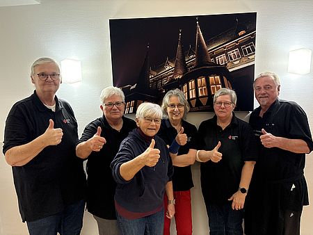 Sechs Mitglieder des DRK-Ortsvereins Einbeck mit dunkelblauen DRK-T-Shirts stehen nebeneinander und lachen in die Kamera und zeigen einen Daumen nach oben als Zeichen der Freude über die vielen Menschen, die Blut gespendet haben
