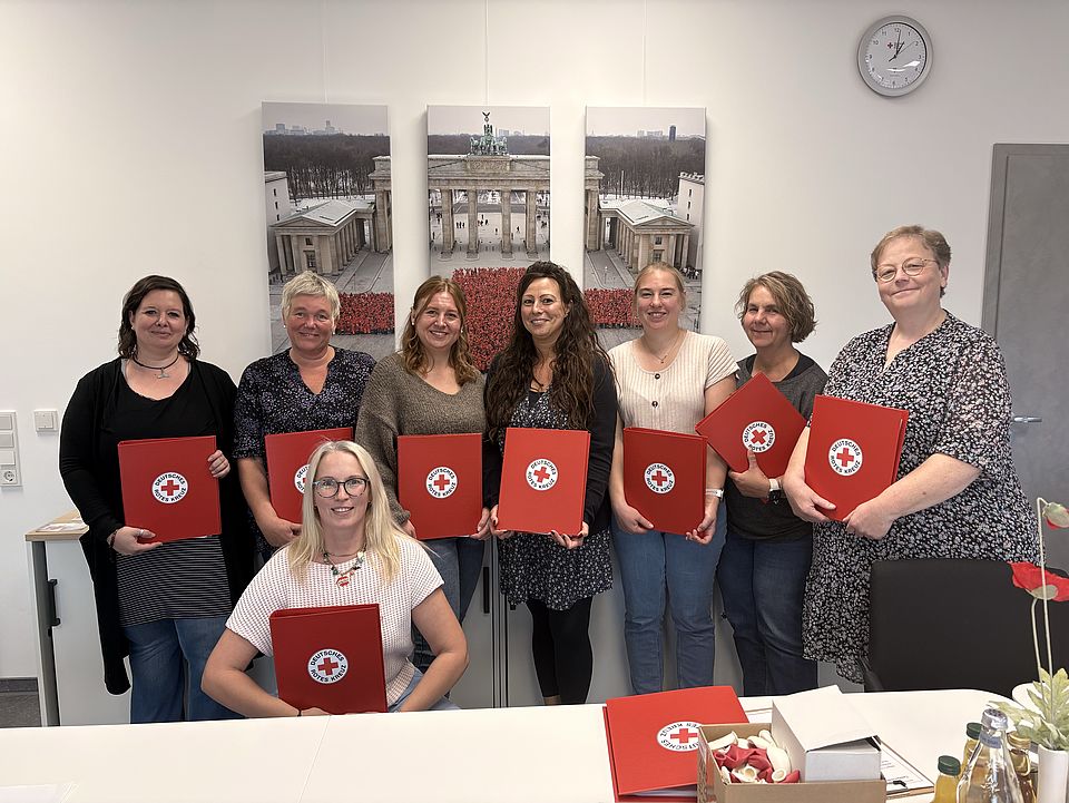 2026_10_01_Teamtag_Kita_Löwenhagen__2_.jpg Gruppenaufnahme der Mitarbeitenden der Kita Löwenhagen und der DRK-Kita-Fachberatung bei einem Teamtag zur Übernahme der Trägerschaft durch den DRK-Kreisverband Göttingen-Northeim. Die Teilnehmenden stehen und sitzen in einem Besprechungsraum und halten rote DRK-Mappen in den Händen.