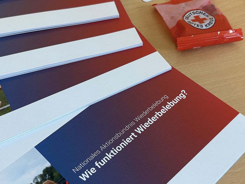 2026_09_21_Woche_der_Wiederbelebung__3_.jpg Auf einem Tisch liegen mehrere Broschüren mit dem Titel „Wie funktioniert Wiederbelebung?“ sowie weiteres Informationsmaterial des Deutschen Roten Kreuzes. Die Unterlagen informieren über die wichtigsten Schritte der Herz-Lungen-Wiederbelebung