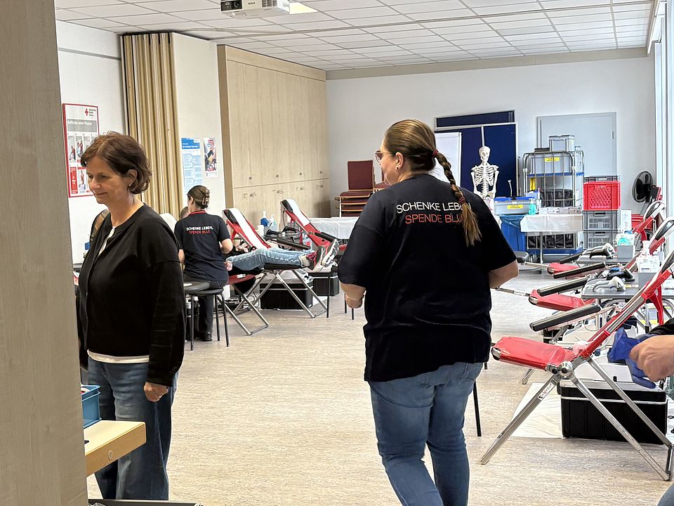 Blutspendeaktion beim DRK-Kreisverband Göttingen-Northeim e. V., Blutspenderaum mit roten Liegen und Mitarbeitende des DRK-Blutspendedienstes