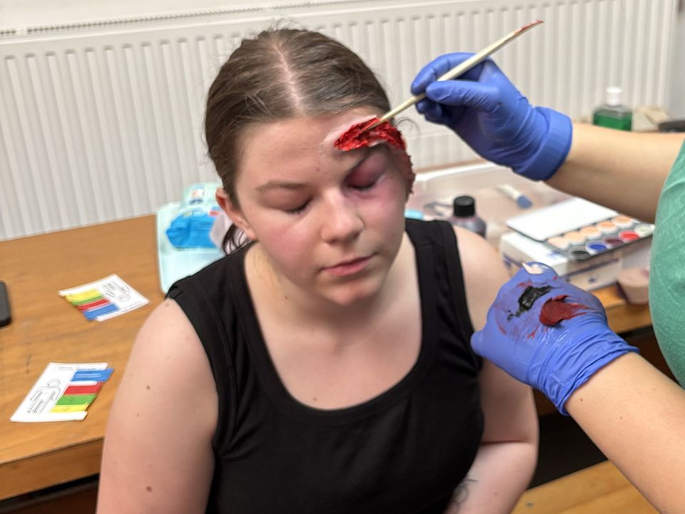 Realistische Unfalldarstellerin wird mit Wunde am Kopf geschminkt