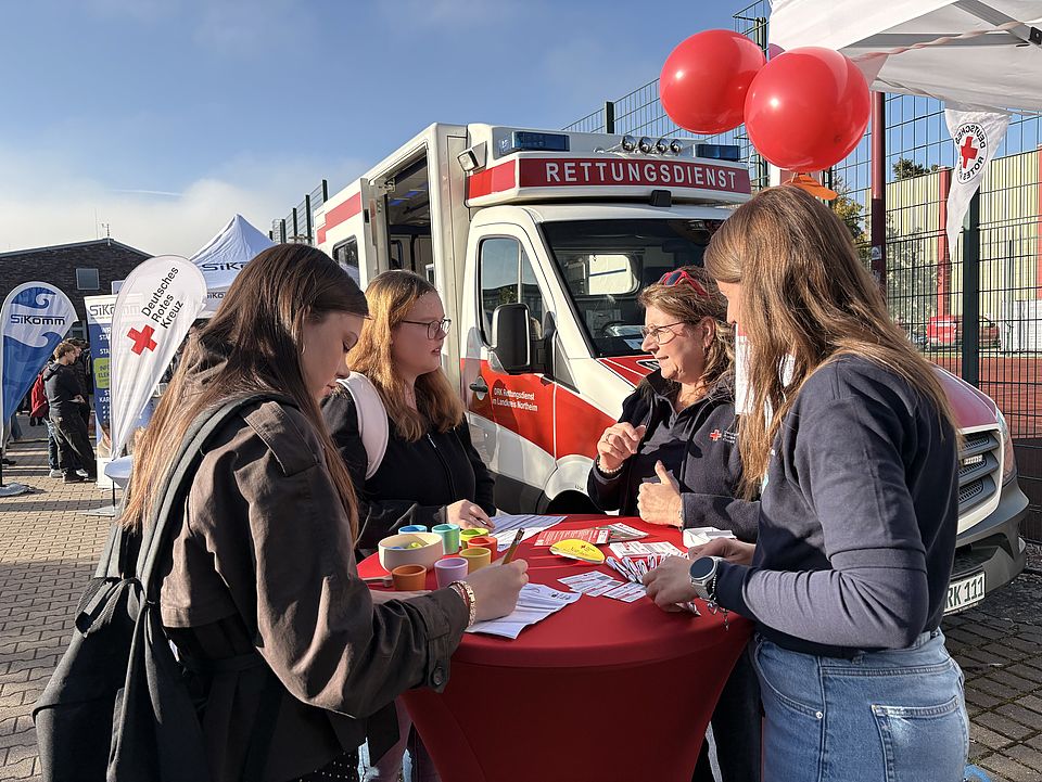 Schülerinnen informieren sich am DRK-Stand auf der Einbecker Ausbildungsmesse mit Rettungswagen im Hintergrund
