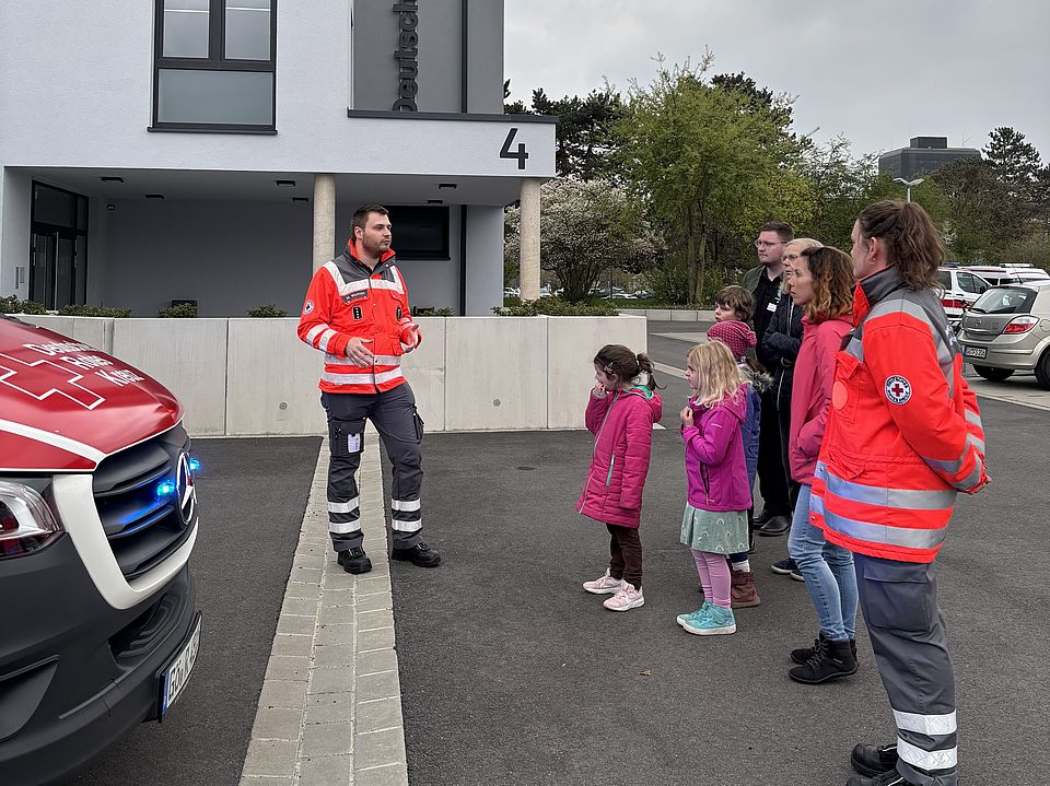 Ehrenamtliche der DRK‑Bereitschaft Göttingen erklären Kindern und Erwachsenen der Evangelischen Familienbildungsstätte Aufgaben des Rettungsdienstes und des Katastrophenschutzes vor dem DRK‑Gebäude