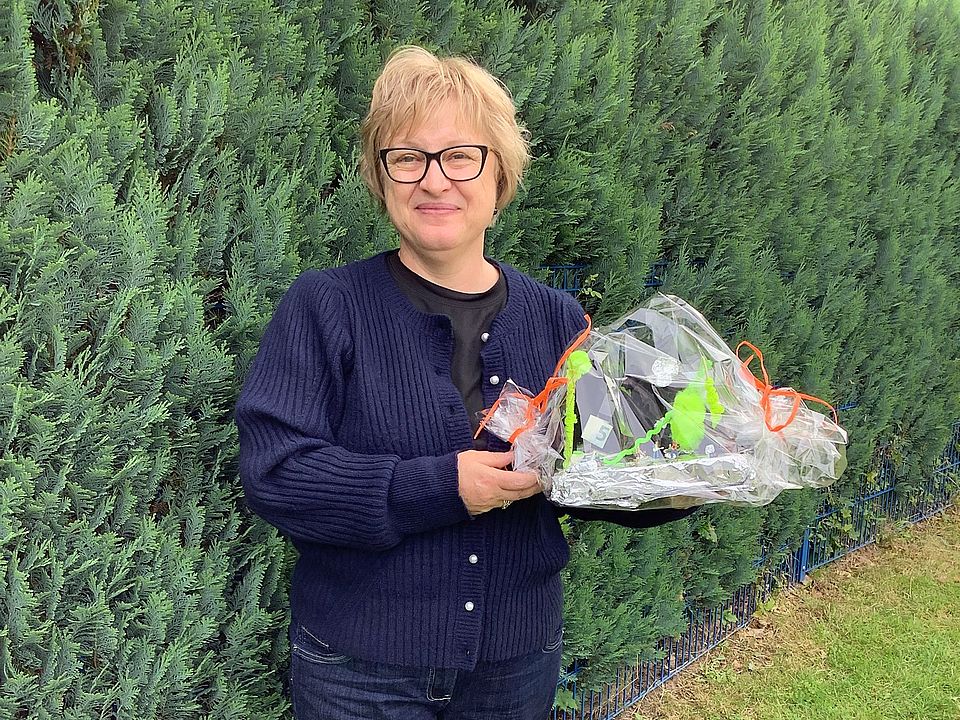 Erzieherin Svetlana Vogel im DRK-Heilpädagogischen Kindergarten mit einem Blumenstrauß in der Hand, im Grünen, lächelt in die Kamera